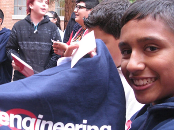 student smiling, holding up a UA t-shirt